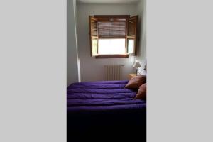 a bedroom with a purple bed and a window at Apartamento Rústico VILLA MOCA Bubión in Bubión