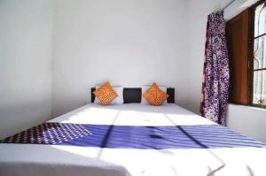 a bedroom with a bed with blue sheets and orange pillows at Vamoose Srishti - Chamoli in Gopeshwar