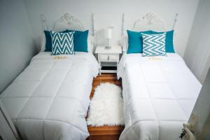two beds in a room with blue and white pillows at Casa A Boleriña in Combarro