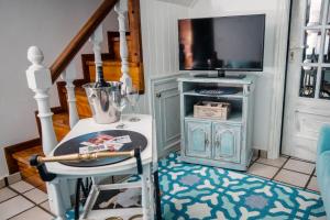 een woonkamer met een televisie en een tafel met een kruk bij Casa A Boleriña in Combarro