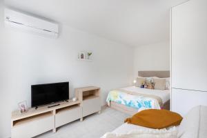 a white room with a tv and a bed at Modern Studio @ Palácio de Cristal in Porto