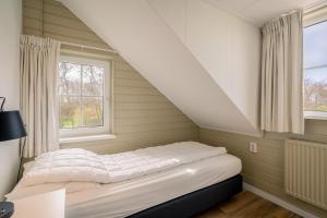 una cama en una habitación con dos ventanas en Annabella 11, en De Koog