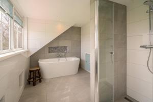 y baño con bañera blanca y ducha. en Annabella 11, en De Koog 10 fotos más