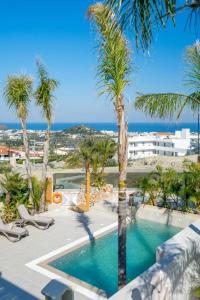 a swimming pool with palm trees and the ocean at Venezia Luxury Living Villas, Faliraki in Faliraki