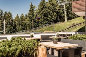 un patio esterno con tavoli, sedie e alberi di Josef Mountain Resort a Avelengo