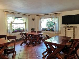 a dining room with tables and chairs and a flat screen tv at Raza Soarelui in Moieciu de Sus