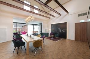 a dining room and living room with a table and chairs at Alexianer Hotel am Wasserturm in Münster