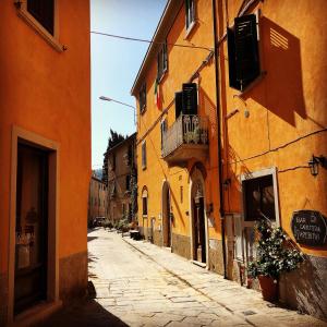 an alley in an old town with orange buildings at Anitta GuestHouse in Castagneto Carducci