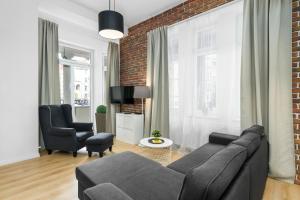 a living room with a couch and a brick wall at Apartment Poznan MTP Chełmońskiego by Renters in Poznań
