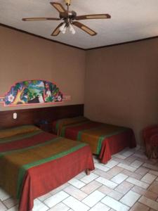 a hotel room with two beds and a ceiling fan at Hotel Regis in Uruapan del Progreso