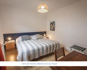 a bedroom with a bed with a striped blanket and a desk at Gîte de Fanfan in Barèges