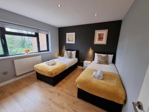 a bedroom with two beds and a window at Crown Meadow - 4 Bedroom House - Heathrow - ExcellentStays in Colnbrook