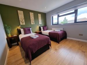 a room with two beds and a window at Crown Meadow - 4 Bedroom House - Heathrow - ExcellentStays in Colnbrook