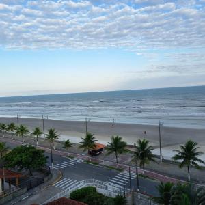 a view of a beach with palm trees and the ocean at Ótimo apartamento condomínio frente a praia in Mongaguá