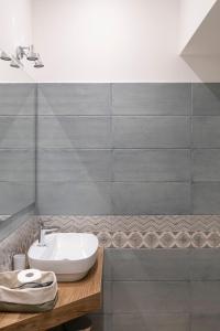 a bathroom with a white sink and a tile wall at Via Goletta Home in Sciacca