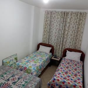 a room with two beds and a curtain at Ótimo apartamento condomínio frente a praia in Mongaguá