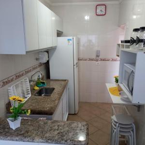a kitchen with a sink and a refrigerator at Ótimo apartamento condomínio frente a praia in Mongaguá