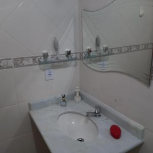 a bathroom with a sink and a mirror at Ótimo apartamento condomínio frente a praia in Mongaguá
