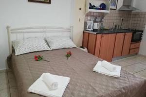 a bed with two white towels and red flowers on it at LORENTZIA ROOM in Batsi