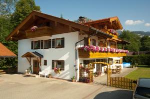 een groot wit huis met bloemen op de gevel bij Landhaus Eschenbach in Schönau am Königssee