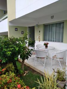 a patio with a white table and chairs and plants at condominio moradas de guarajuba in Guarajuba