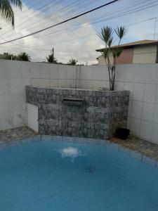 a swimming pool with a stone fireplace in a house at condominio moradas de guarajuba in Guarajuba