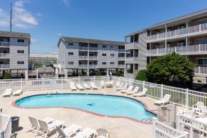 a swimming pool with lounge chairs and a building at Tiffanie By The Sea in Ocean City