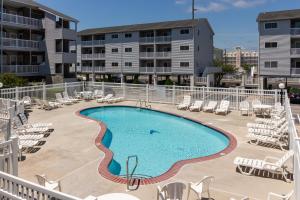 a swimming pool with lounge chairs and a building at Tiffanie By The Sea in Ocean City