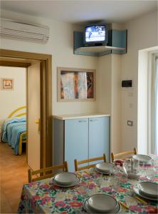 uma sala de jantar com uma mesa com cadeiras e uma televisão em Appartamenti Mimi em Lido di Jesolo