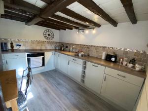 uma cozinha com armários brancos e uma bancada em Thatch Cottage, East Boldre nr Beaulieu and Lymington em Brockenhurst