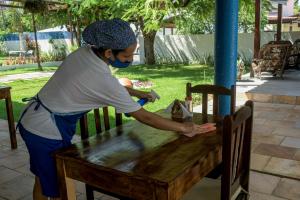 a woman is standing at a wooden table at Pousada São Jorge in Porto De Galinhas