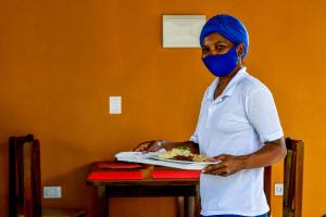 a man wearing a mask holding a plate of food at Pousada São Jorge in Porto De Galinhas