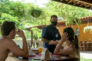 a man wearing a face mask and a woman sitting at a table at Pousada São Jorge in Porto De Galinhas
