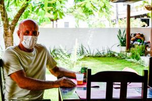 a man in a mask sitting at a table with a drink at Pousada São Jorge in Porto De Galinhas