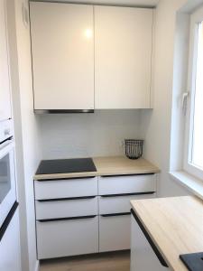 a kitchen with white cabinets and a counter top at Apartament Blisko Morza i Parku Gdańsk Brzeźno in Gdańsk