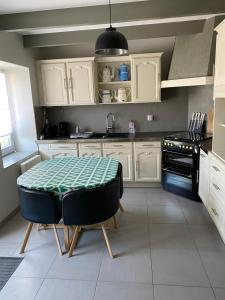 a kitchen with white cabinets and a table in it at La Petite Maison in Saint-Nicolas-du-Pélem