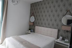 ein Schlafzimmer mit einem weißen Bett und zwei Spiegeln in der Unterkunft Fűzi-Lizi Apartman in Balatonfůzfő