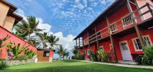 ein rotes Gebäude mit Palmen davor in der Unterkunft Casas Pé na Areia - Vista Mar in Porto De Galinhas