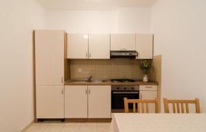 una pequeña cocina con armarios blancos y una mesa en Apartments Ivan, en Dubrovnik