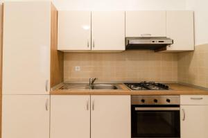 una cocina con armarios blancos y fregadero en Apartments Ivan, en Dubrovnik