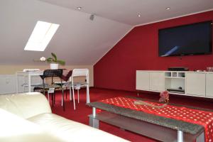 ein Wohnzimmer mit einer roten Wand und einem Flachbild-TV in der Unterkunft Loft Apartments Pulheim in Pulheim