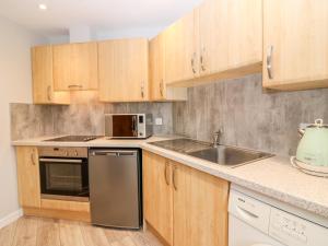 a kitchen with wooden cabinets and a sink at Gairnlea Cottage in Ballater