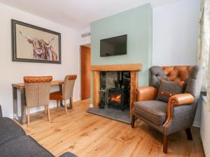 a living room with a fireplace and a table and chairs at Gairnlea Cottage in Ballater