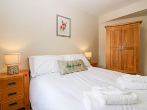 1 dormitorio con cama blanca y armario de madera en Gairnlea Cottage, en Ballater