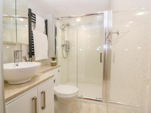a bathroom with a shower and a toilet and a sink at Gairnlea Cottage in Ballater +4 photos