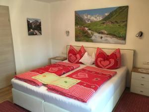 Schlafzimmer mit einem Bett mit roten und weißen Kissen in der Unterkunft Gästehaus Schmid in Sankt Johann im Saggautal