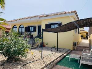 a small yellow house with a straw roof at Vivienda Vacacional TINIZARA in Arona