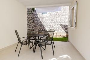 una mesa y sillas en un patio con una pared en Apartments Ivan, en Dubrovnik