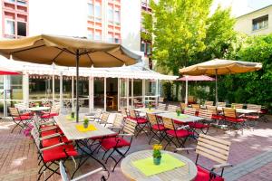 een patio met tafels, stoelen en parasols bij ACHAT Hotel Neustadt an der Weinstraße in Neustadt an der Weinstraße