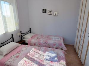 1 dormitorio con 2 camas con sábanas rosas y ventana en Phoebes Place At Kalamaki Court, 2 Bedroom Villa With A Shared Pool, en Kalamaki